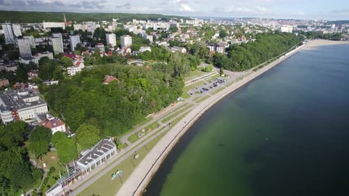 Aerial view showing shoreline of Baltic Sea in Gdynia City with apartment blocks, forest and downtow
