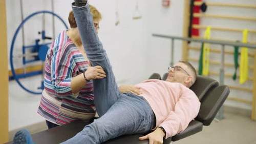 Physical Therapist Performing Leg Stretching Exercise with Patient in Rehabilitation Clinic