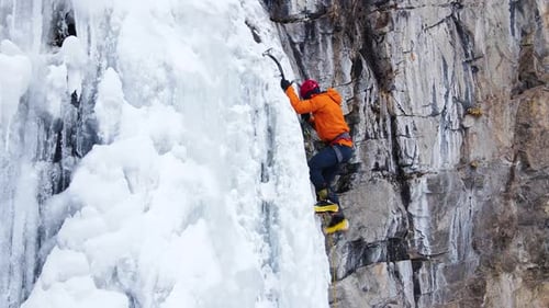 Ice Climber Ascends Frozen Waterfall on Mountain
