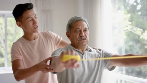 Senior Man Exercising with Therapy Band at Home