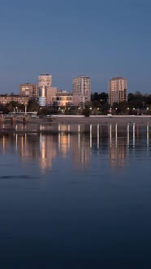 Lights Of A Big City On The River Bank During Sunset And Nightfall