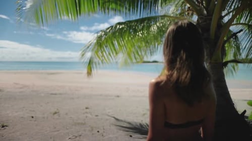 Young Woman Standing Under Palm Tree Enjoying Tropical Beach View