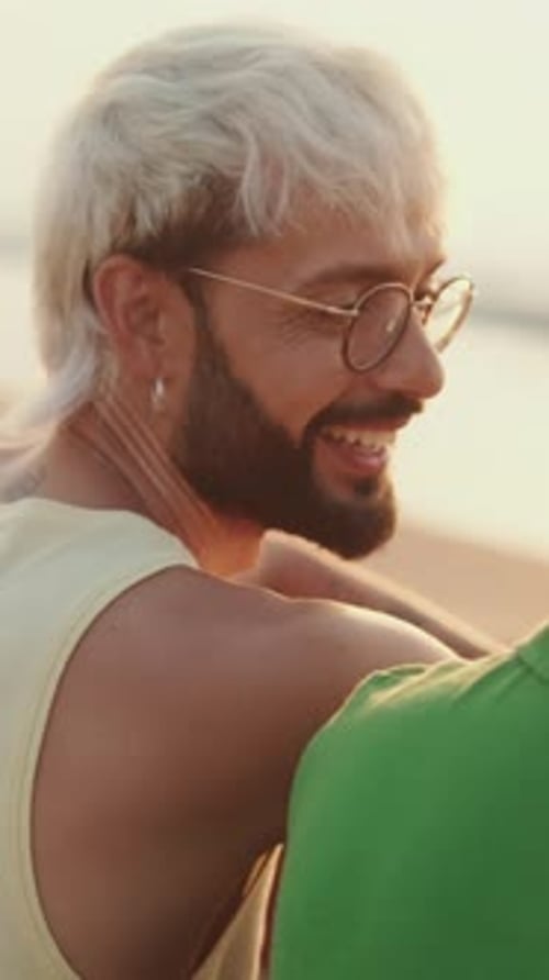 De perto, casal homossexual apaixonado passa tempo juntos sentados na praia ao nascer do sol