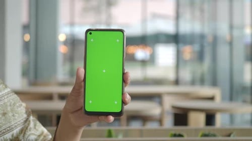 A Smartphone in a Modern Workspace Shows a Vibrant Green Screen