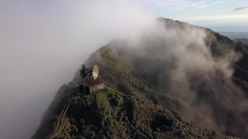 Aerial pulls back from abandoned radar tower on Hawaii jungle mountain