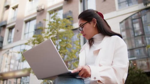 Young Woman Working on Laptop Outdoors in City