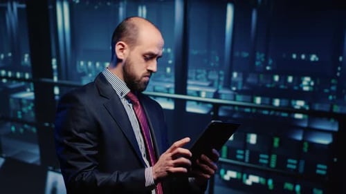 Young Adult Businessman Uses Tablet in Server Room