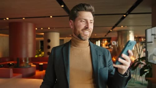 Smiling Man Using Phone in Hotel Lobby