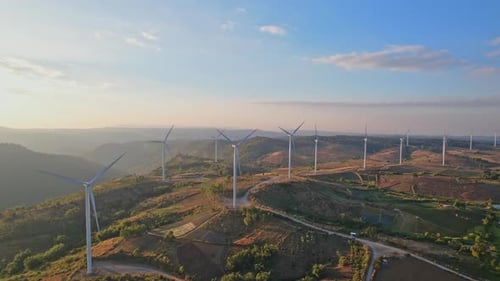 Aerial drone shot flying outdoors above the wind turbine field.