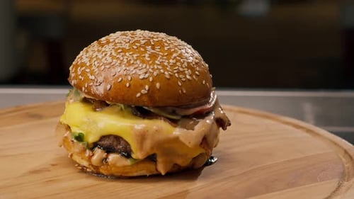A close-up of a juicy burger with beef patty with vegetables and cheese cooked in the kitchen