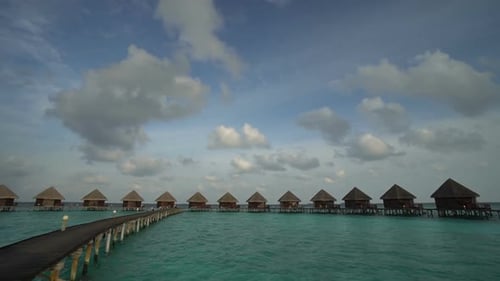 Panoramic shot of bungalow huts in sea on a tropical resort with blue sky and clouds as background