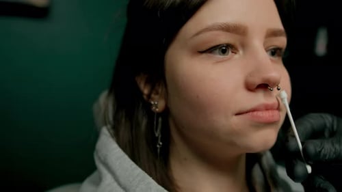 Interior de un estudio de piercings: el maestro de piercings hace un piercing para una niña, piercing para el tabique nasal