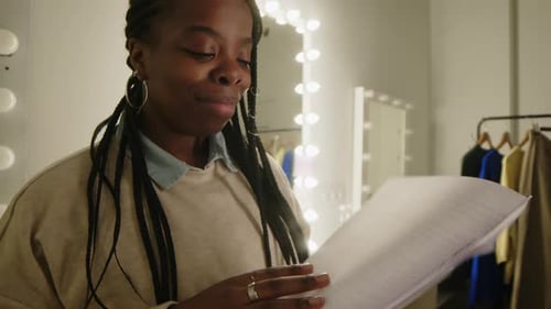Young Woman Reads Script in Dressing Room