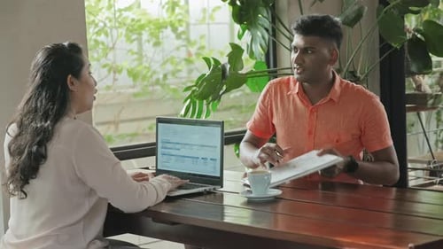 Coworkers Using Laptop and Discussing Business Plan in Cafe