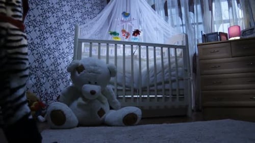 La cuna para bebés está cerca de un oso de juguete en la habitación