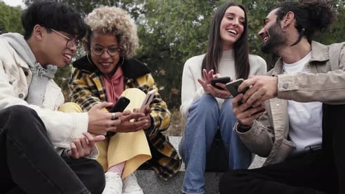 Friends Together Using Mobile Phones in Urban Park