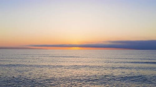 Mar Negro y playa cercanos contra un cielo con nubes y un sol al amanecer