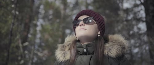 Woman walking through the pine forest on a sunny winter day.
