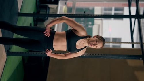 Vertical Video in a Sports Club Trainer in a Black Top and Leggings Stands and Poses Smiling