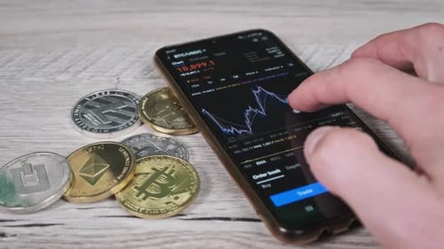 Hand Using Smartphone to View Cryptocurrency Line Graph