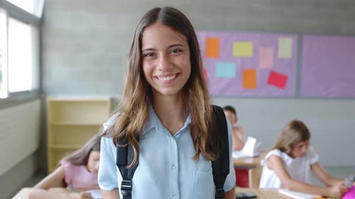 Smiling Primary School Student Girl with Backpack Standing at Classroom
