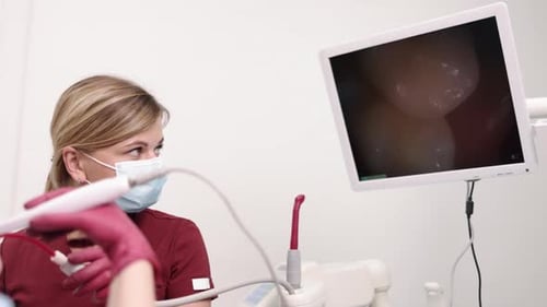 Dental Professional Inspecting Teeth with Monitor Display