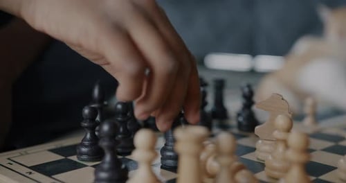 Closeup of Hands Child and Adult Playing Chess Moving Pieces on Board Concentrated on Game Indoors