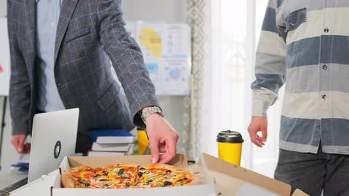 Office Workers Smiling While Eating Pizza and Drinking Coffee at Desk