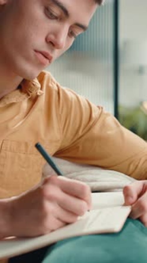 Young Adult Writes in Notebook at Home