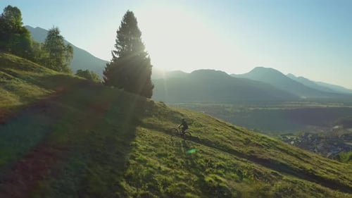 Aerial view of a biker with MTB E-bike biking up the hill with a beautiful view.