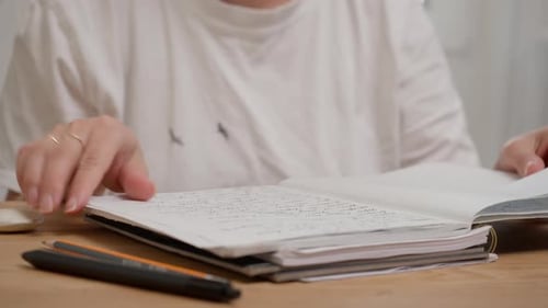Woman Flipping Through Pages of an Overstuffed Notebook