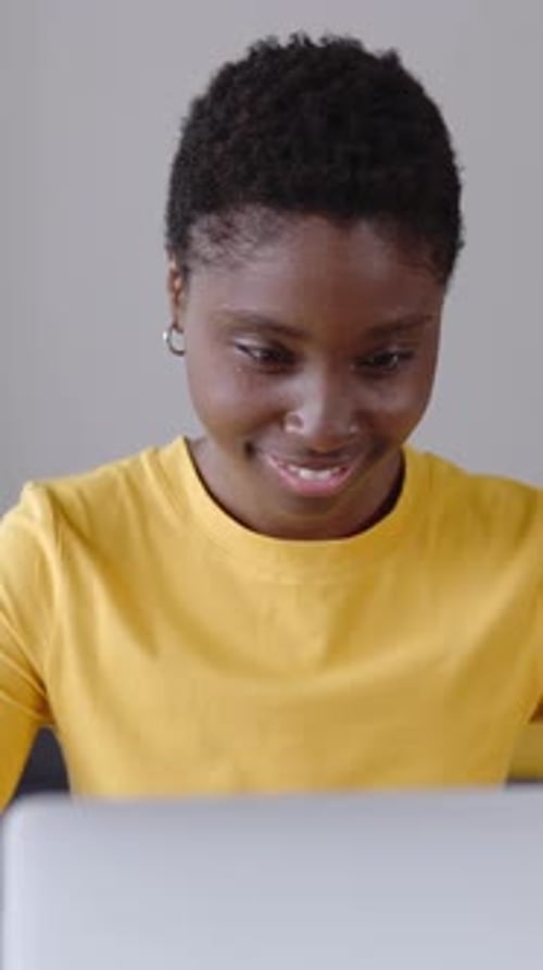 Woman Smiling While Using Laptop Indoors