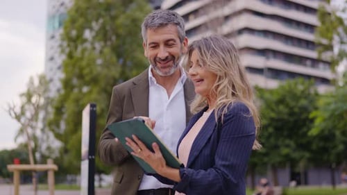 Business Colleagues Discussing Work on a Tablet Outdoors