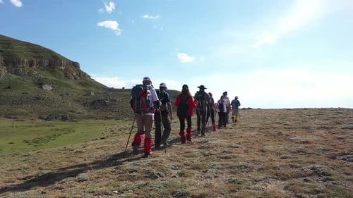Group Of People Walking On Green Mountain