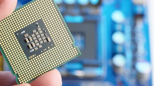 Hand holding microchip CPU Processor and placing in motherboard socket blurred, Extreme macro