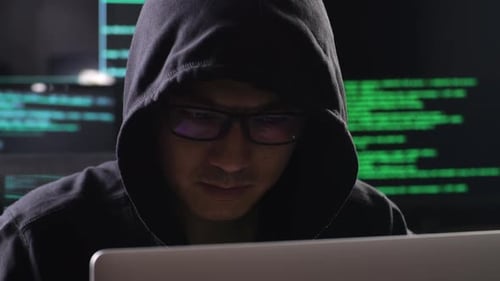 Primer plano de un hacker asiático en un barrio tomando café mientras trabaja en una computadora portátil con mapas y datos