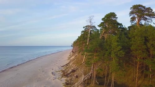 Beautiful aerial establishing view of Baltic sea coast on a sunny evening, golden hour, beach with w