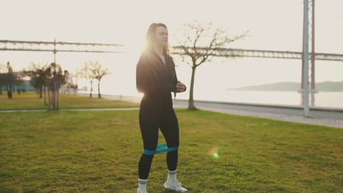 Fit Woman Does Squats with Resistance Band Outdoors