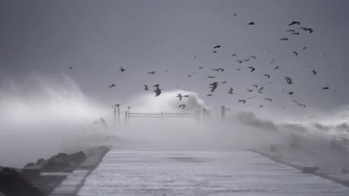 Massive waves crashing over pier during extreme storm with gale-force winds