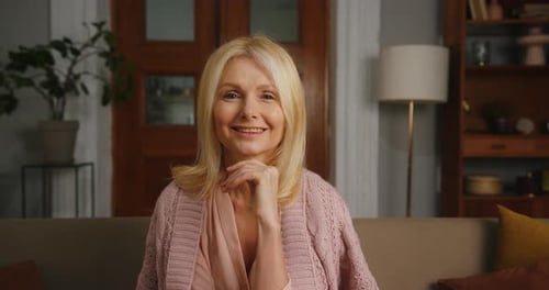 Smiling Senior Woman Sits on Couch Indoors