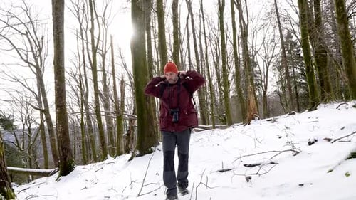 Hiker putting on his hood while walking in snowy forest