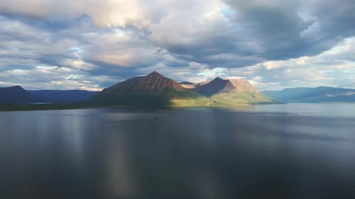 Aerial View of Lake Lama and Sunlit Mountain Ridge Under Dramatic Clouds