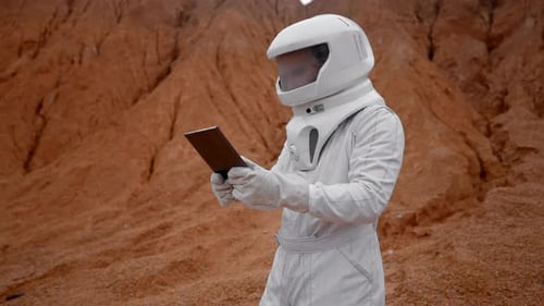 Dolly Out of an Astronaut Working on Laptop on a Unknown Red Surface Planet