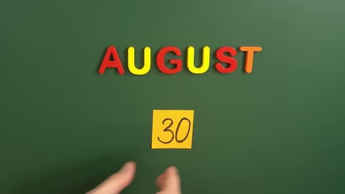 Hand sticking a sticker 30 August calendar day on school board. 30 date of august. Thirtieth day