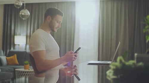 Man Uses Laptop and Phone at Home