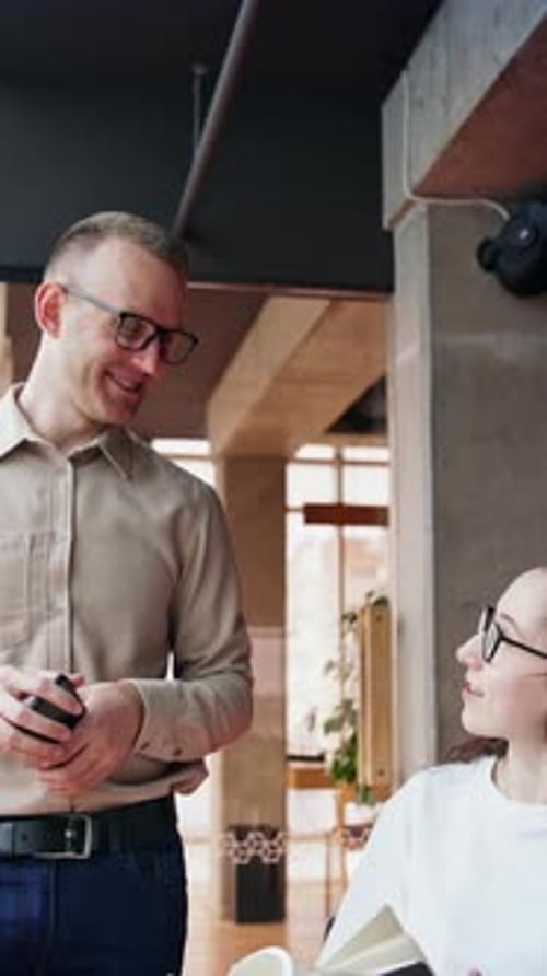 Female and male colleagues cheerfully talk in the office.