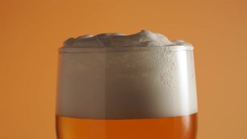 Rotierendes Bierglas. Bier einschenken. Glas Bier mit Schaum.