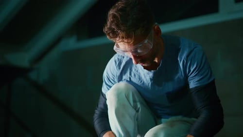 Un technicien blanc prépare un joint métallique avec un outil à main dans un espace de travail mansardé avec des gants de mesure minutieux