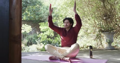 Caucasian man practicing yoga meditation on terrace in sunny nature, slow motion