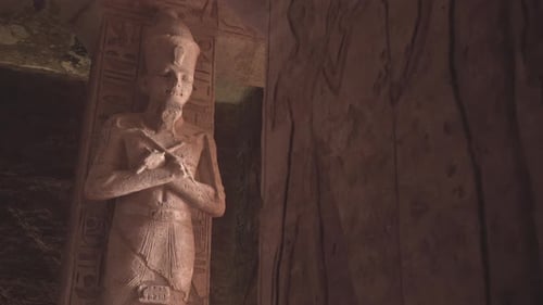 Egyptian statues and hieroglyphics inside a temple.
